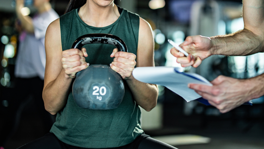 Person performing kettlebell exercise with coach guidance in a strength training gym